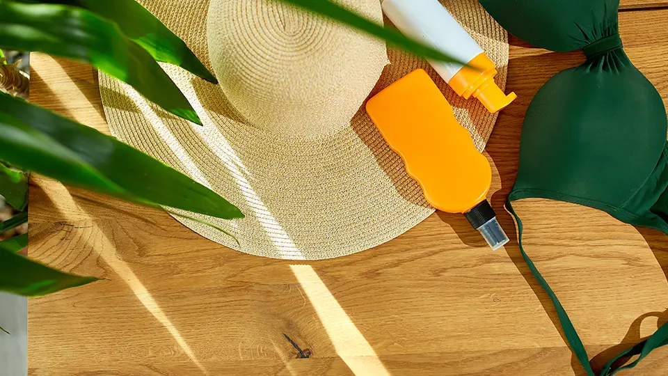 Crema Solar al lado de un bikini para ilustrar la importancia de como proteger la piel del sol en Elda